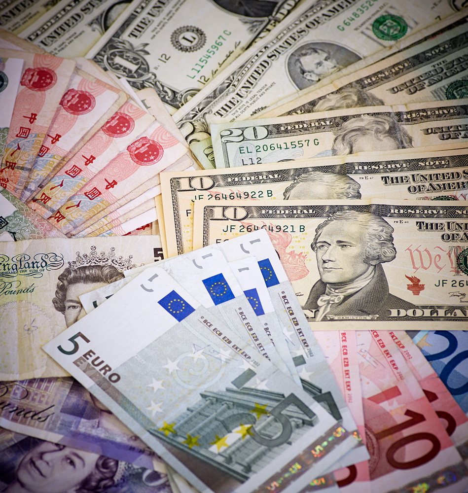 Blandning av olika sedlar från flera valutor spridda över en yta.
