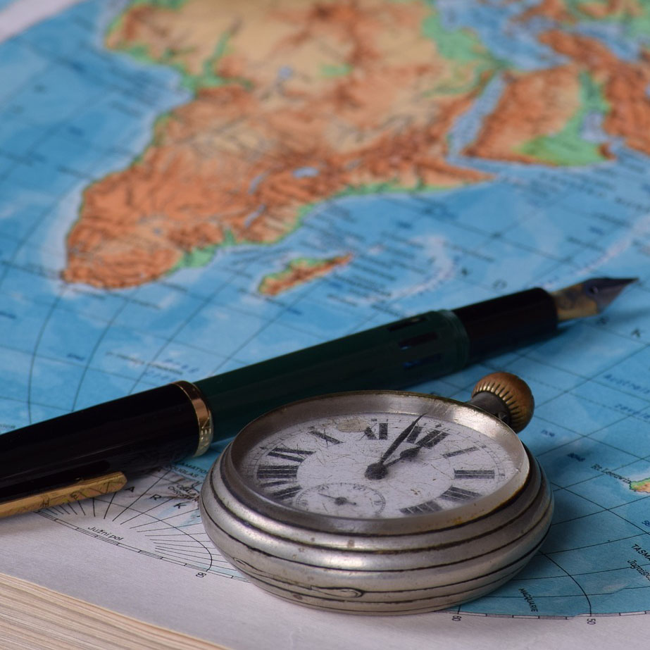 Närbild av en karta med en bläckpenna och ett äldre fickur placerade ovanpå.