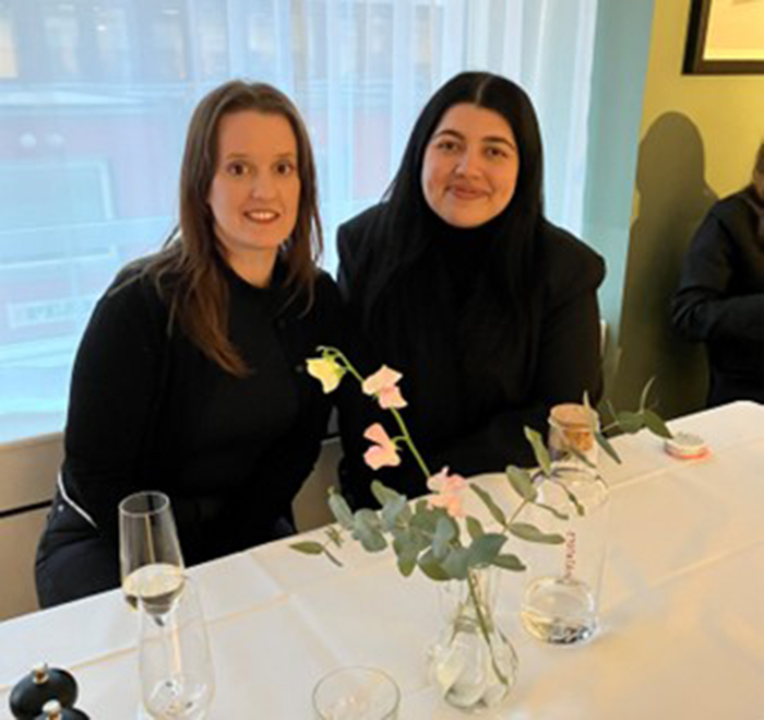 En bild av två personer som sitter vid ett bord och ler mot kameran