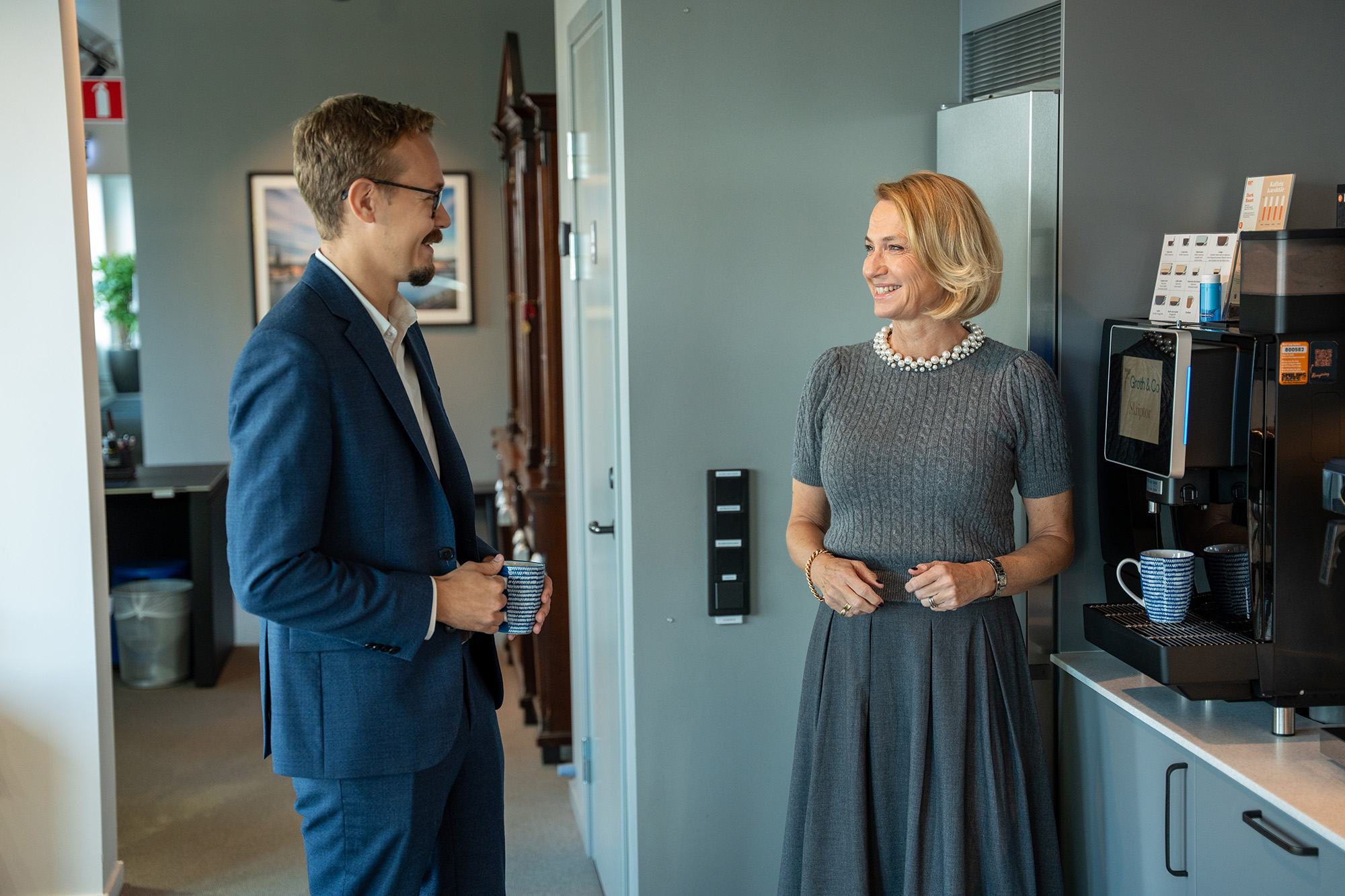 Två personer som konverserar vid en kaffemaskin.