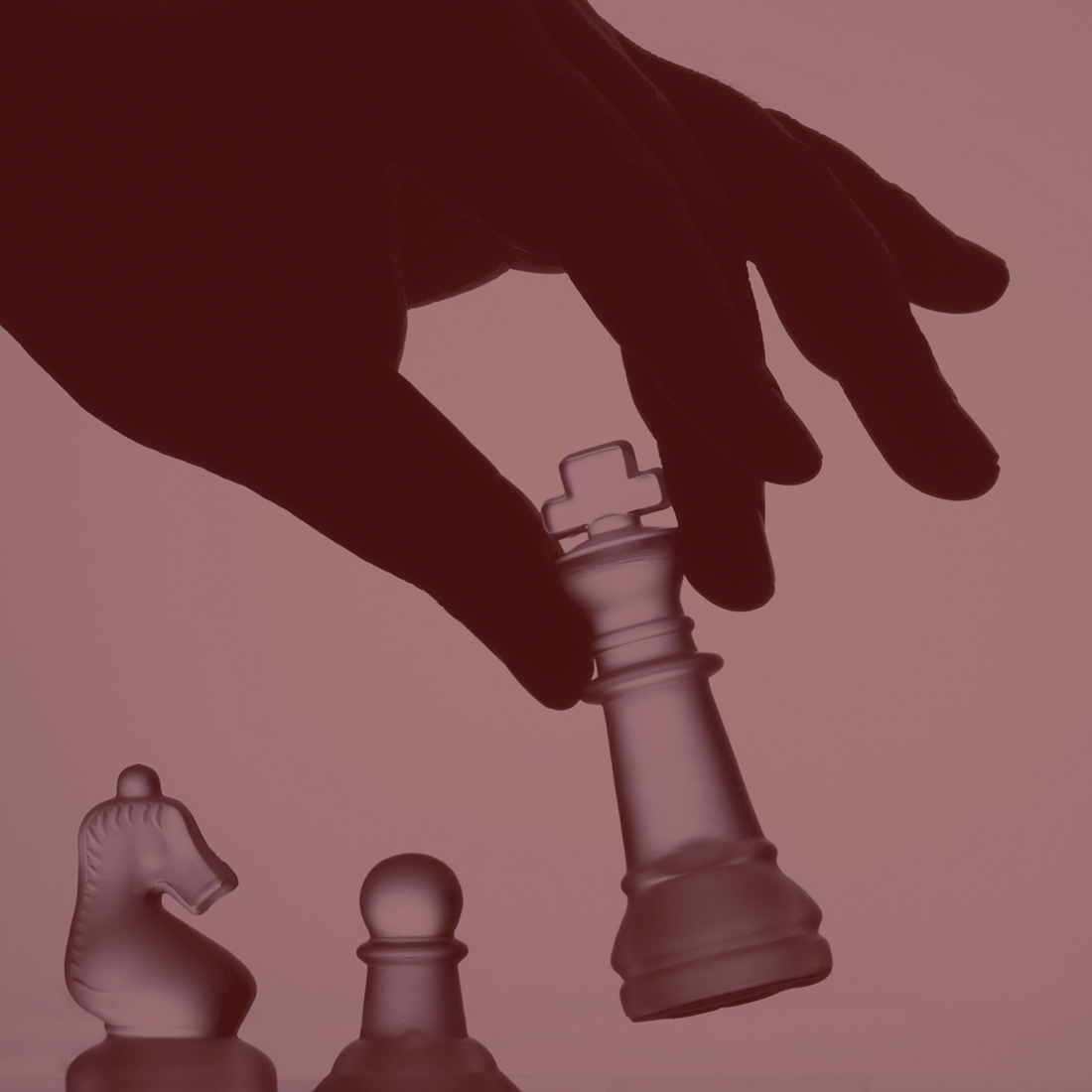 En rödtonad bild a en hand som flyttar en schackpjäs